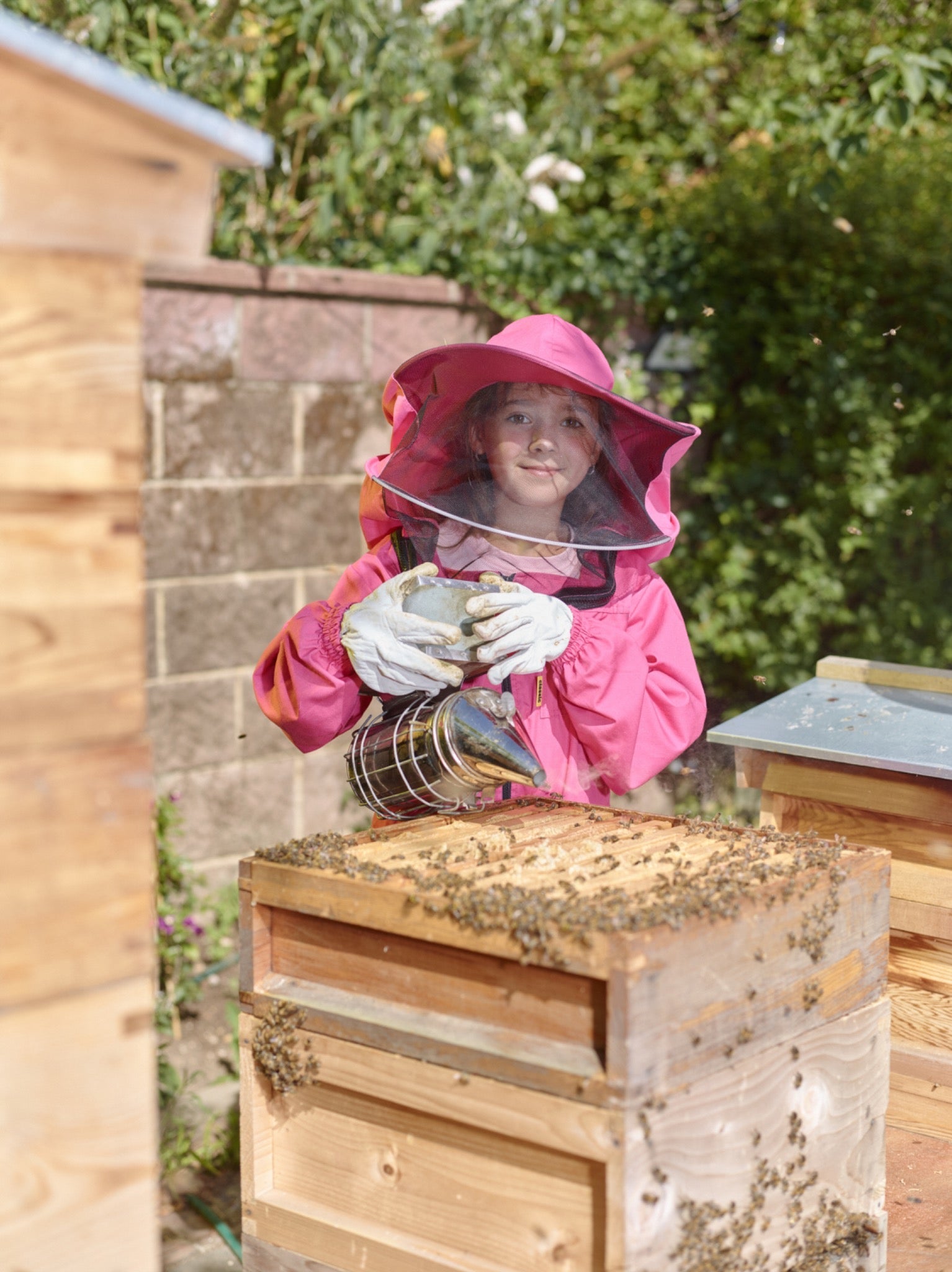 Sofia holding a smoker beside an open hive