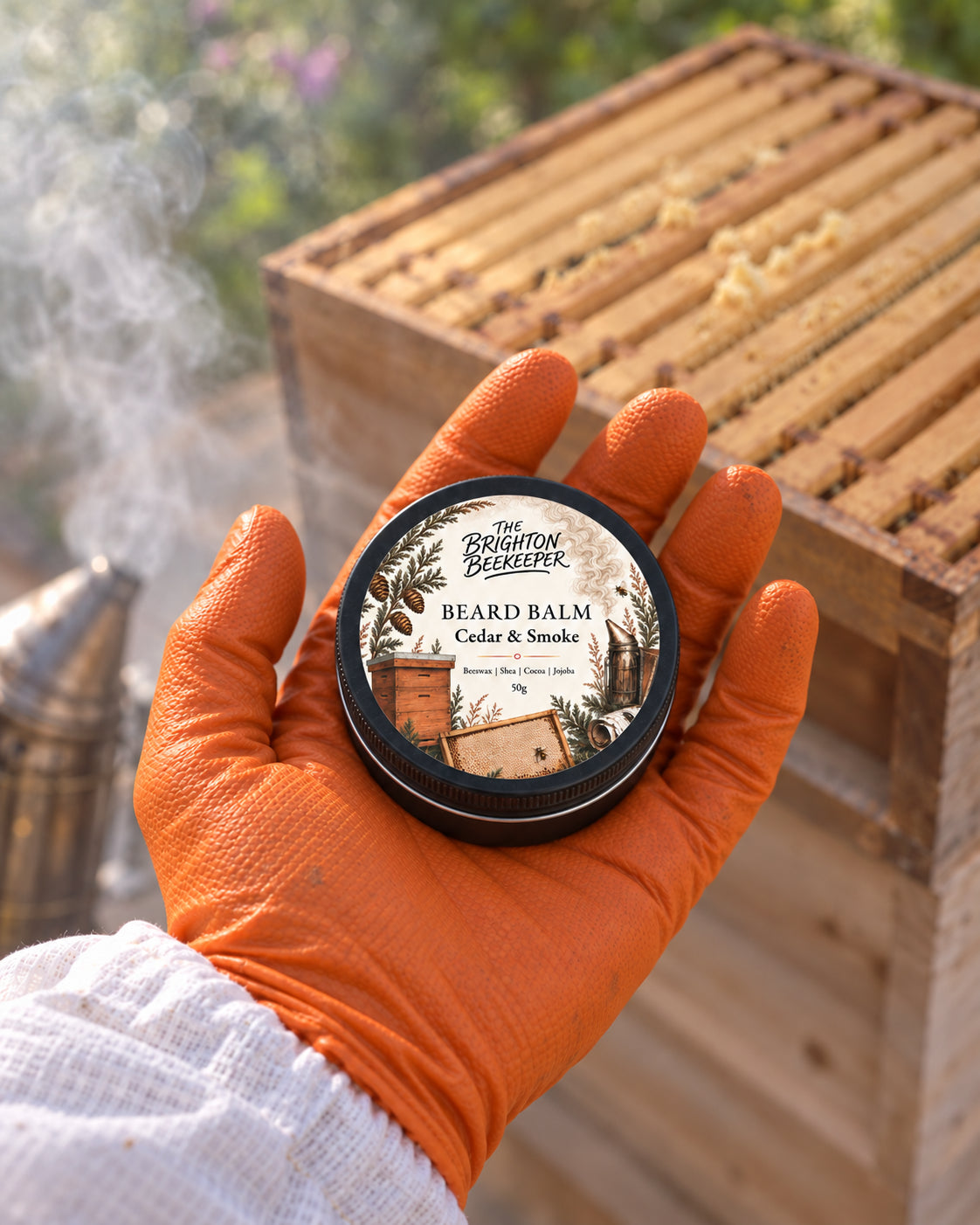 Cedar & Smoke Beard Balm held in an orange beekeeping glove beside an open hive